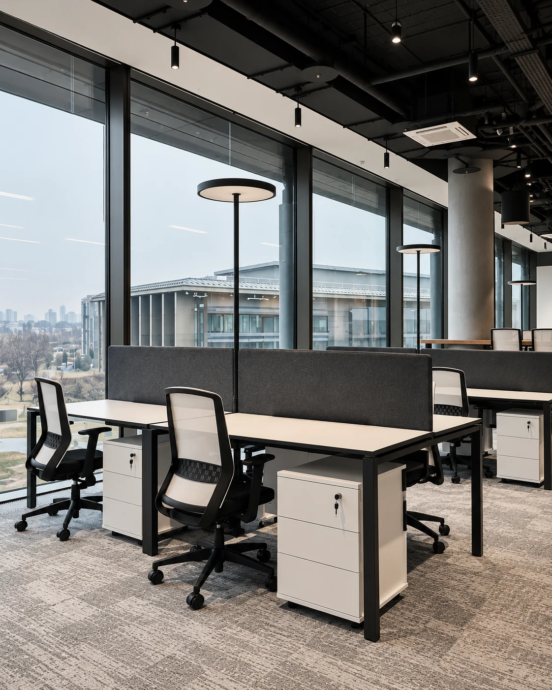 Round-headed office floor lamps beside shared desks in a window-lined workspace
